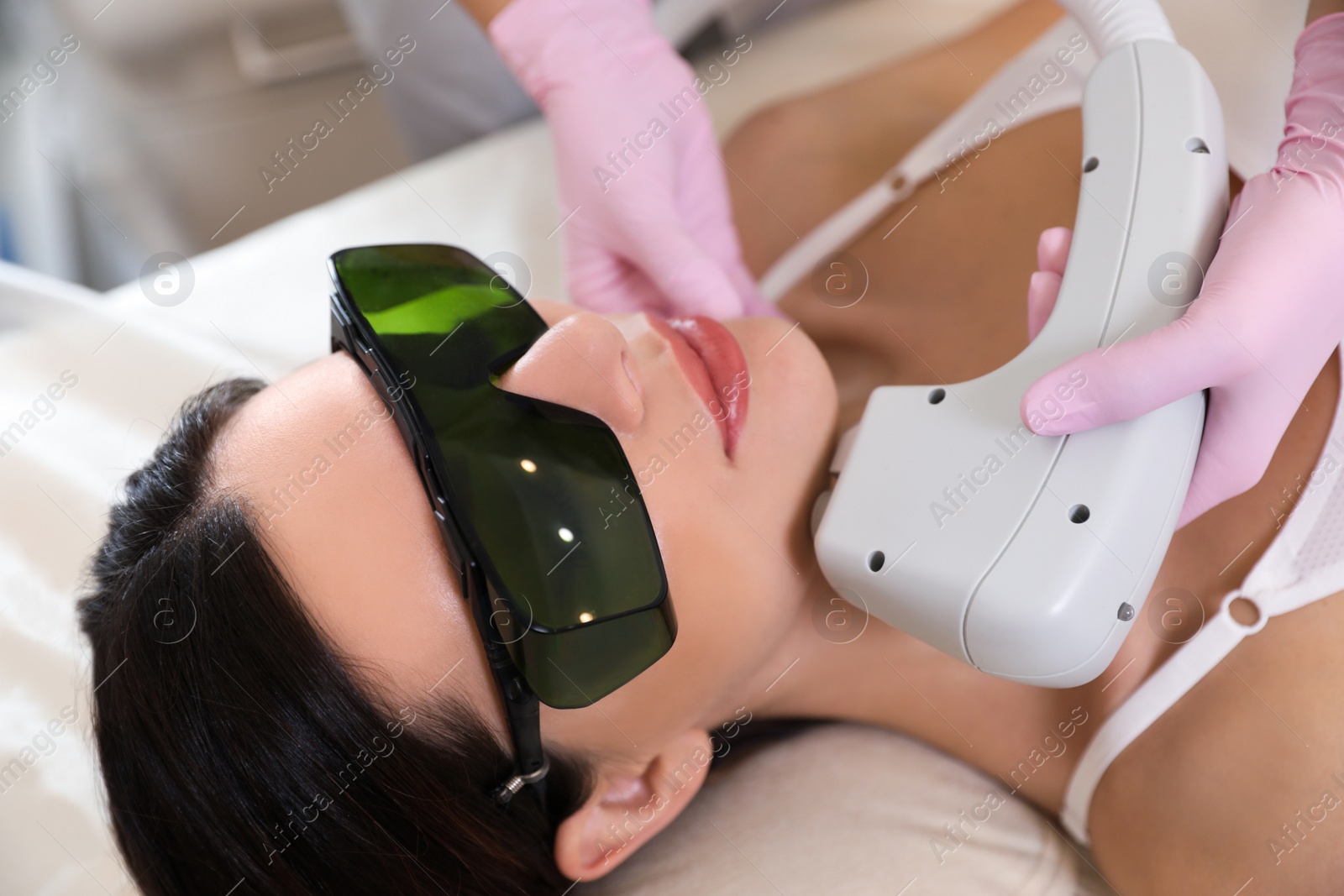 Photo of Young woman undergoing laser epilation procedure in beauty salon