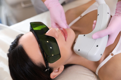 Photo of Young woman undergoing laser epilation procedure in beauty salon