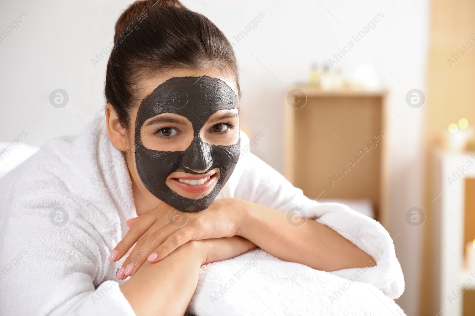 Photo of Beautiful woman with black mask on face relaxing in spa salon. Space for text