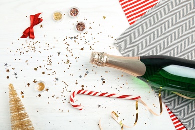 Photo of Christmas composition with bottle of champagne and decor on wooden background, top view