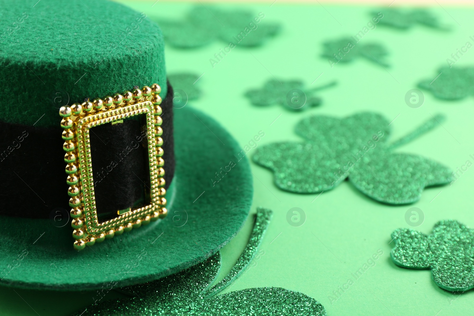 Photo of St. Patrick's day. Leprechaun hat and decorative clover leaves on green background