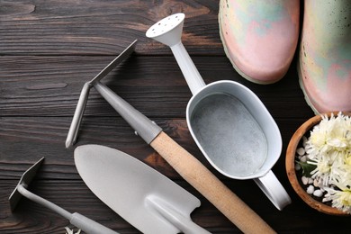 Flat lay composition with watering can and gardening tools on wooden table