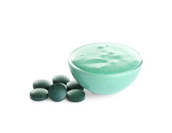 Photo of Freshly made spirulina facial mask in bowl and pills on white background