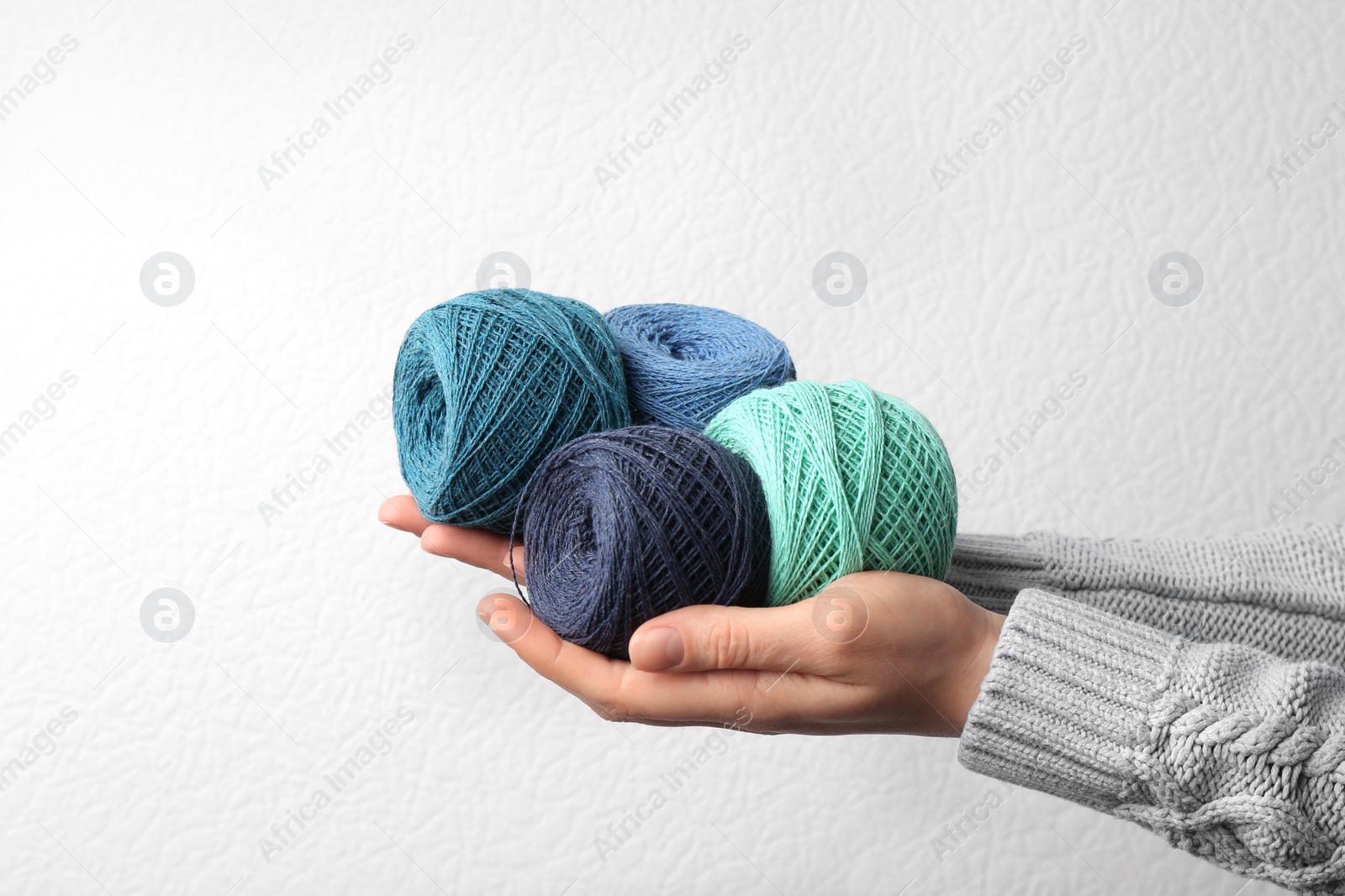 Photo of Woman holding clews of threads against white background, closeup