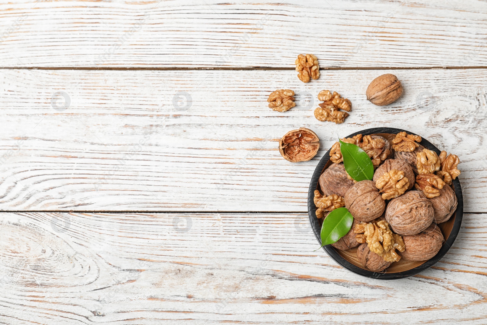 Photo of Plate with walnuts and space for text on wooden background, top view