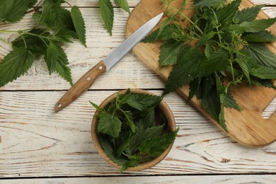 Photo of Fresh stinging nettle leaves on white wooden table, flat lay