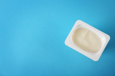 Plastic cup with tasty yogurt on color background, top view