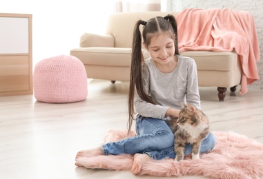 Photo of Cute little girl with cat sitting on floor at home