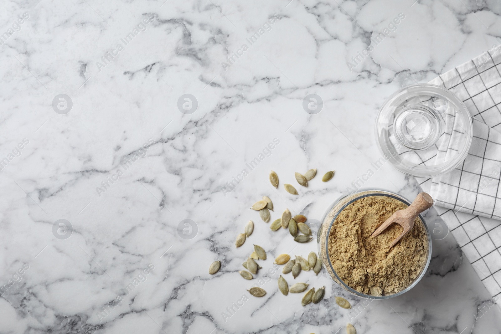 Photo of Jar with pumpkin flour and seeds on marble background