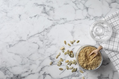 Jar with pumpkin flour and seeds on marble background