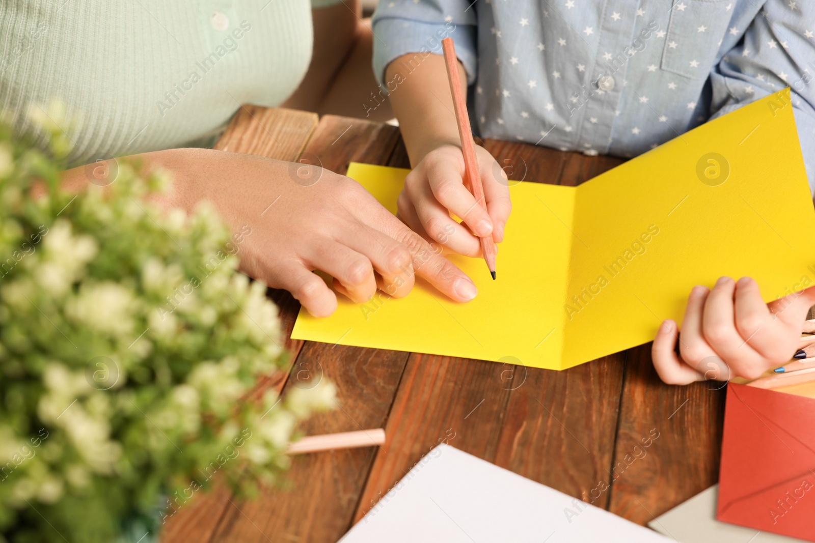 Photo of Little girl with her mother making beautiful greeting card at home, closeup