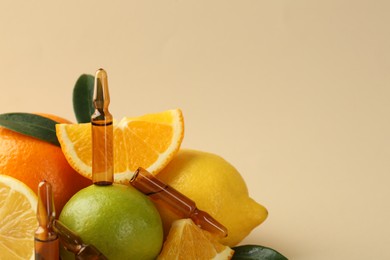 Photo of Skincare ampoules with vitamin C, different citrus fruits and leaves on beige background, closeup. Space for text