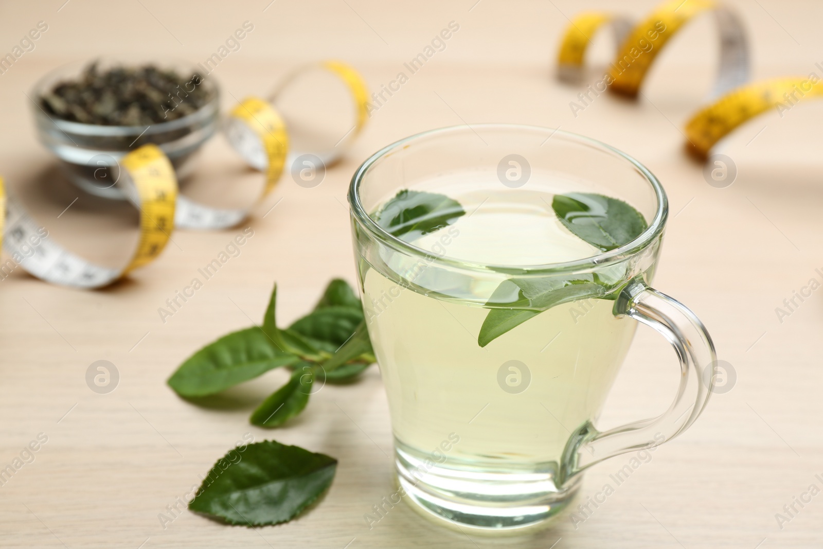 Photo of Diet herbal tea with green leaves on wooden table