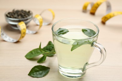 Photo of Diet herbal tea with green leaves on wooden table