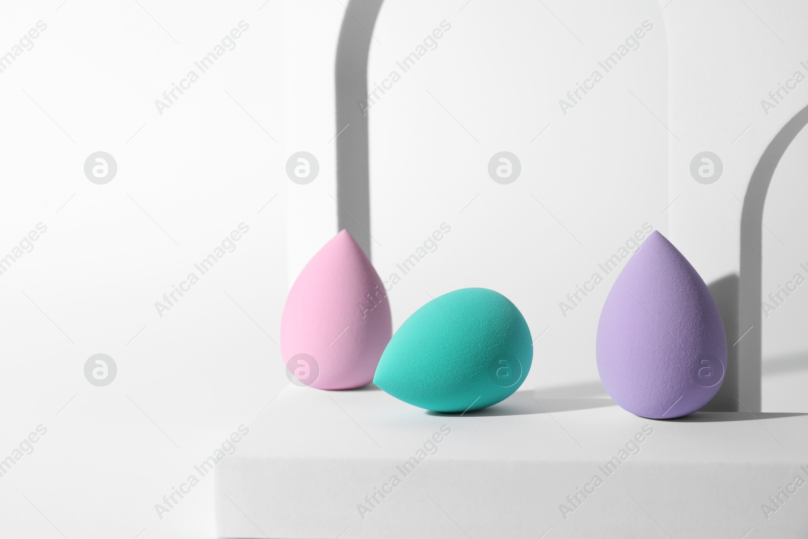 Photo of Stylish presentation of makeup sponges on white background, space for text