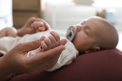 Photo of Mother with her cute sleeping baby at home, focus on hands