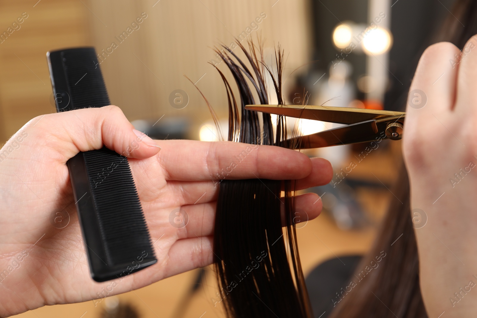 Photo of Hairdresser cutting client's hair with scissors in salon, closeup