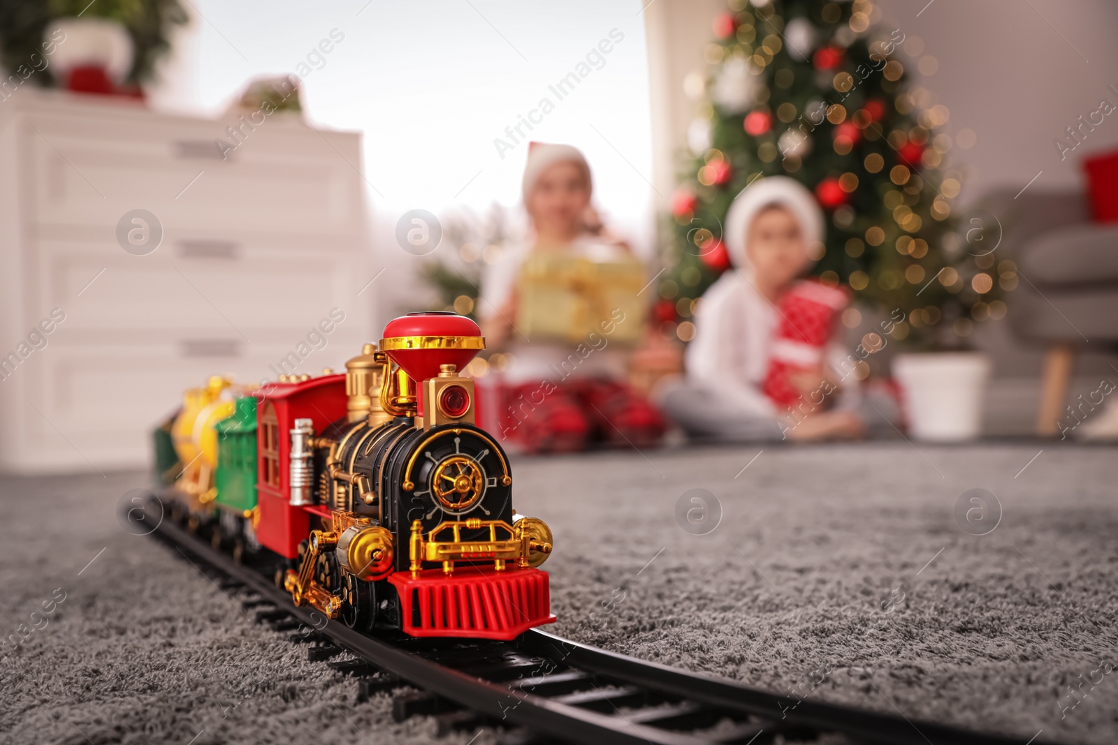 Photo of Children playing with colorful toy in room decorated for Christmas, focus on train