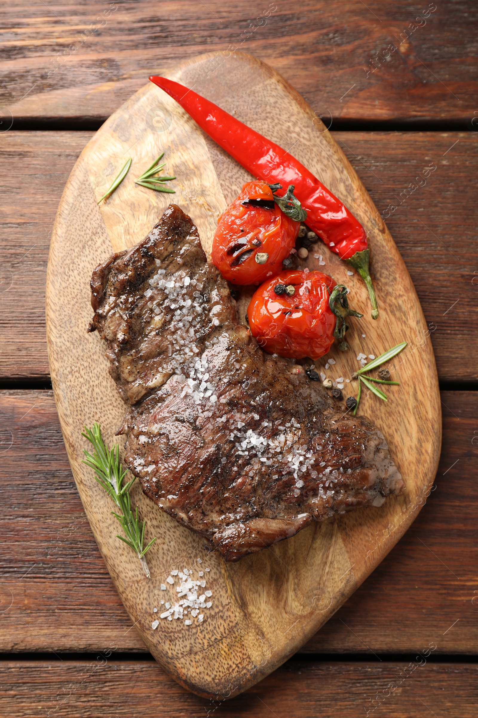 Photo of Delicious roasted beef meat, vegetables and spices on wooden table, top view