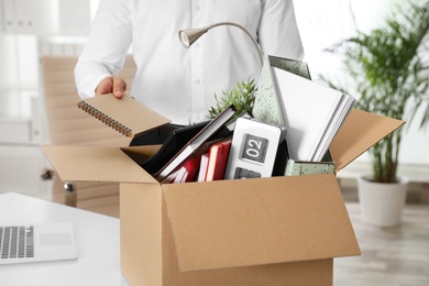 Young man packing stuff in box at office, closeup