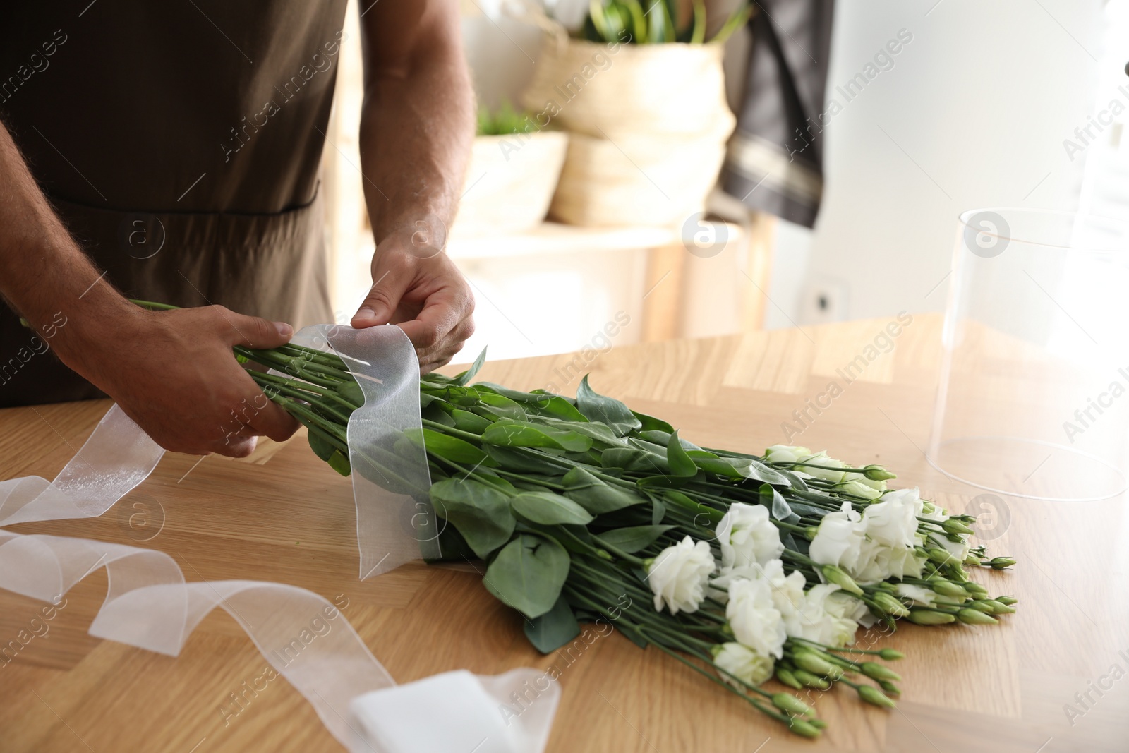 Photo of Florist making beautiful bouquet at table in workshop, closeup