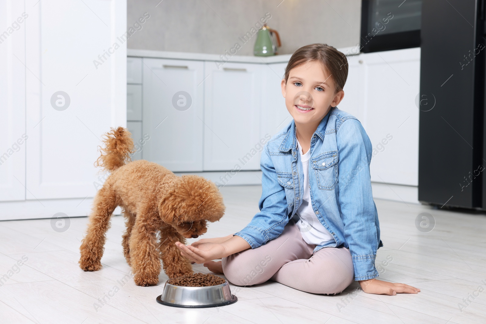 Photo of Little child feeding cute puppy in kitchen. Lovely pet