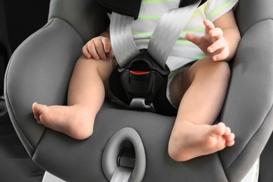 Photo of Little baby in child safety seat inside of car, closeup on legs