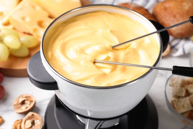 Photo of Pot of delicious cheese fondue and forks on table