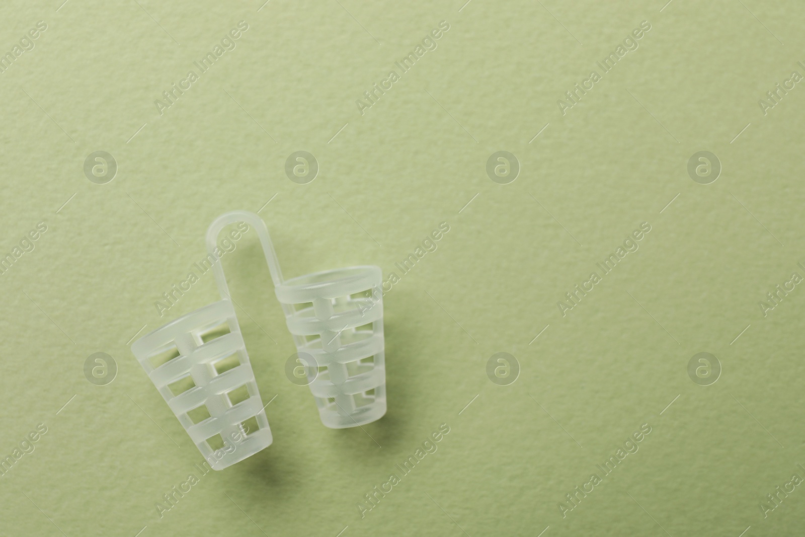 Photo of Nasal anti-snoring device on light green background, top view. Space for text