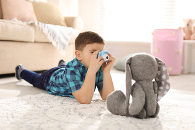 Photo of Little photographer taking picture of toy bunny at home