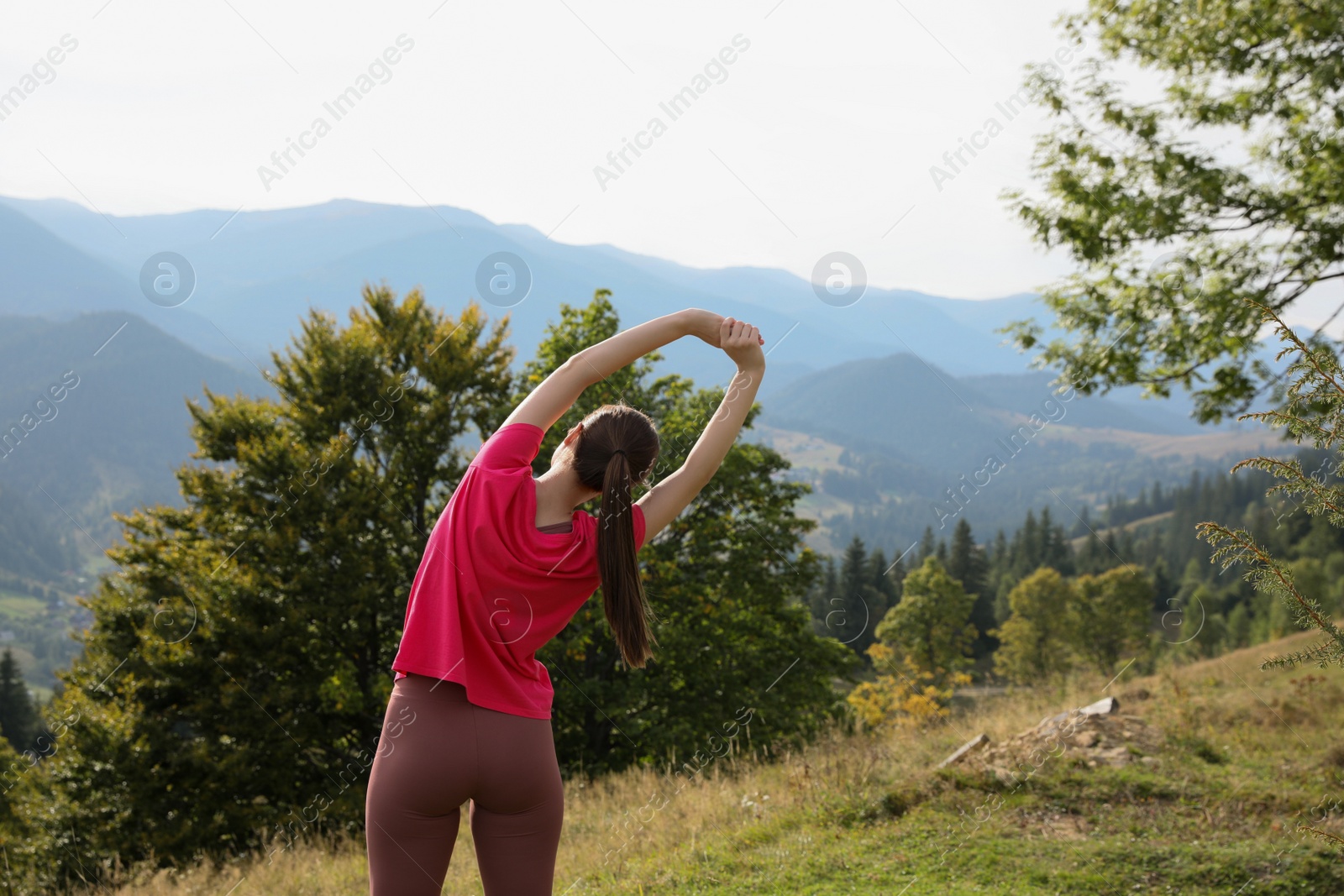 Photo of Woman doing morning exercise in mountains, back view. Space for text