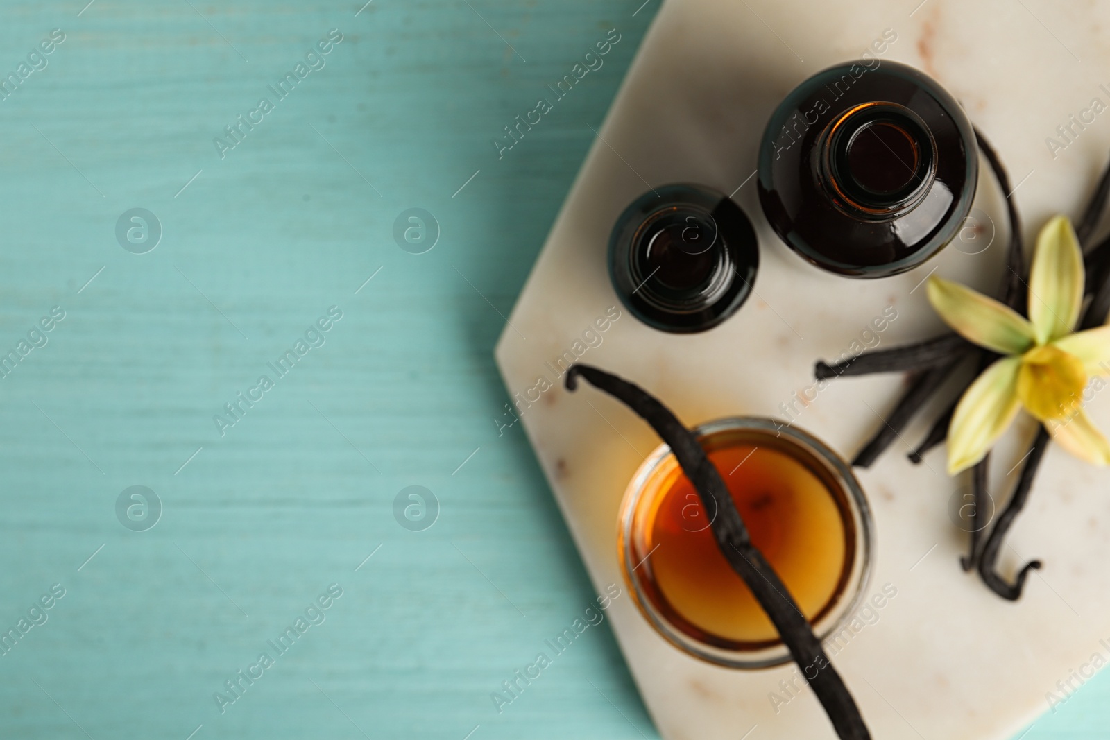 Photo of Flat lay composition with vanilla extract on blue wooden table. Space for text