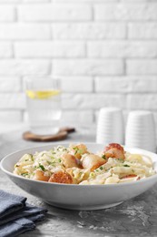 Photo of Delicious scallop pasta with spices in bowl on gray textured table