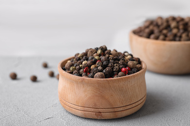 Photo of Different peppercorns on light grey table, closeup