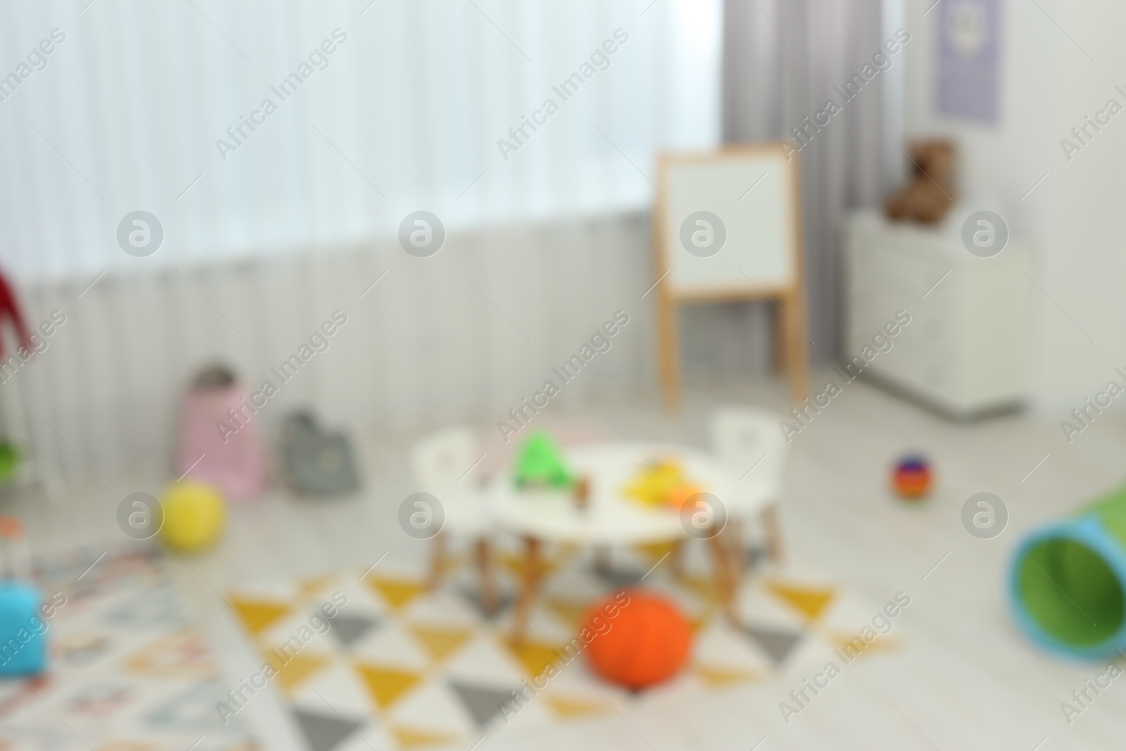 Photo of Blurred view of child`s playroom with different toys and furniture. Stylish kindergarten interior