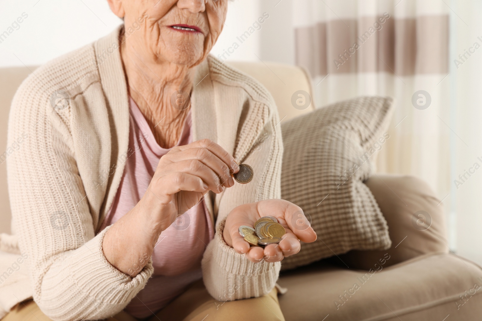Photo of Elderly woman counting coins in living room, closeup