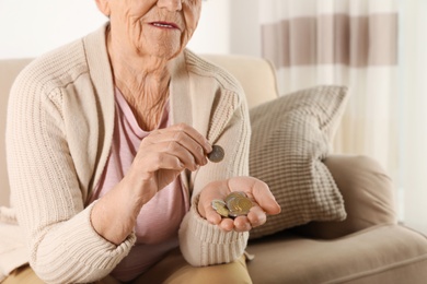 Elderly woman counting coins in living room, closeup