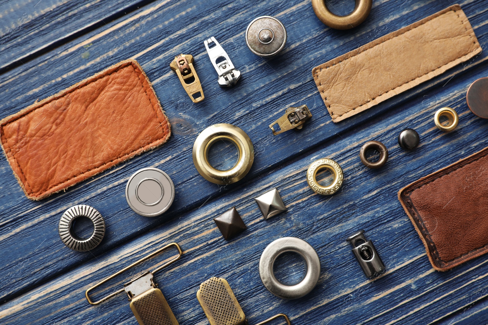 Photo of Flat lay composition with garment accessories for jeans on blue wooden background