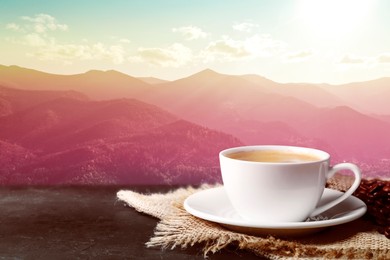 Cup of aromatic hot coffee on black table and beautiful view of mountain landscape. Space for text
