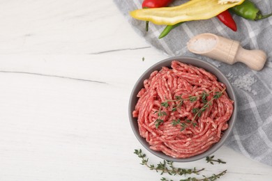 Photo of Flat lay composition with fresh raw ground meat and thyme in bowl on white wooden table. Space for text
