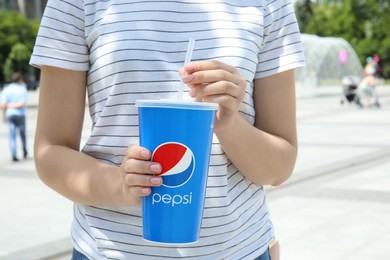 MYKOLAIV, UKRAINE - JUNE 9, 2021: Woman with paper Pepsi cup on city street, closeup