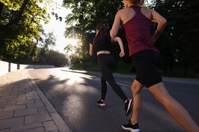 Women running outdoors on sunny day, back view