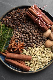 Photo of Different spices, nuts and fir branches on dark gray table, top view