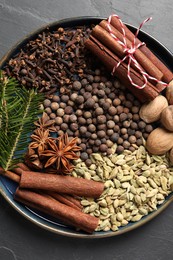 Different spices, nuts and fir branches on dark gray table, top view