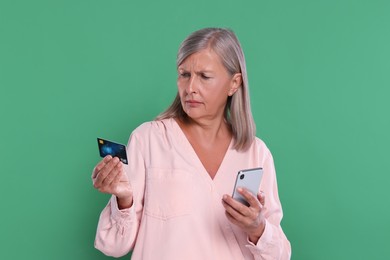Photo of Worried woman with credit card and smartphone on green background. Be careful - fraud