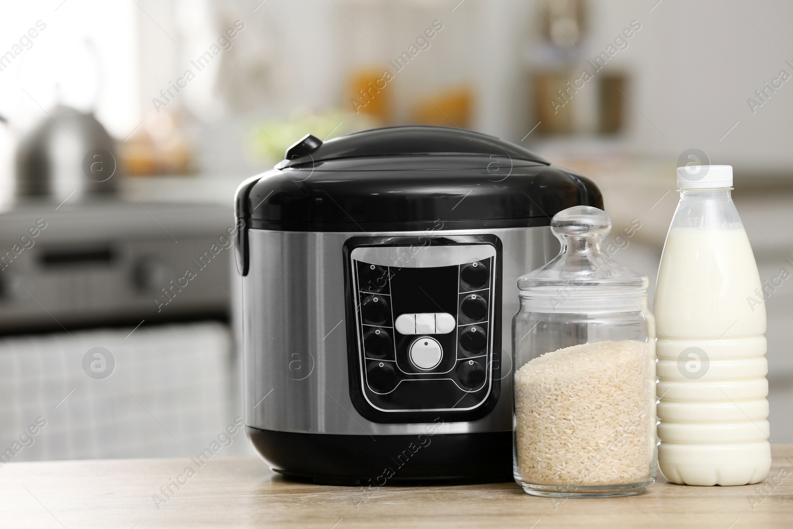Photo of Modern electric multi cooker, rice and milk on table in kitchen