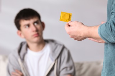 Photo of Father talking with his teenage son about contraception at home, closeup. Sex education concept