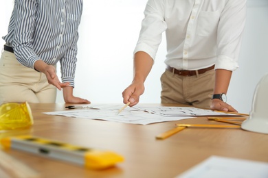 People working with construction drawings at table, closeup