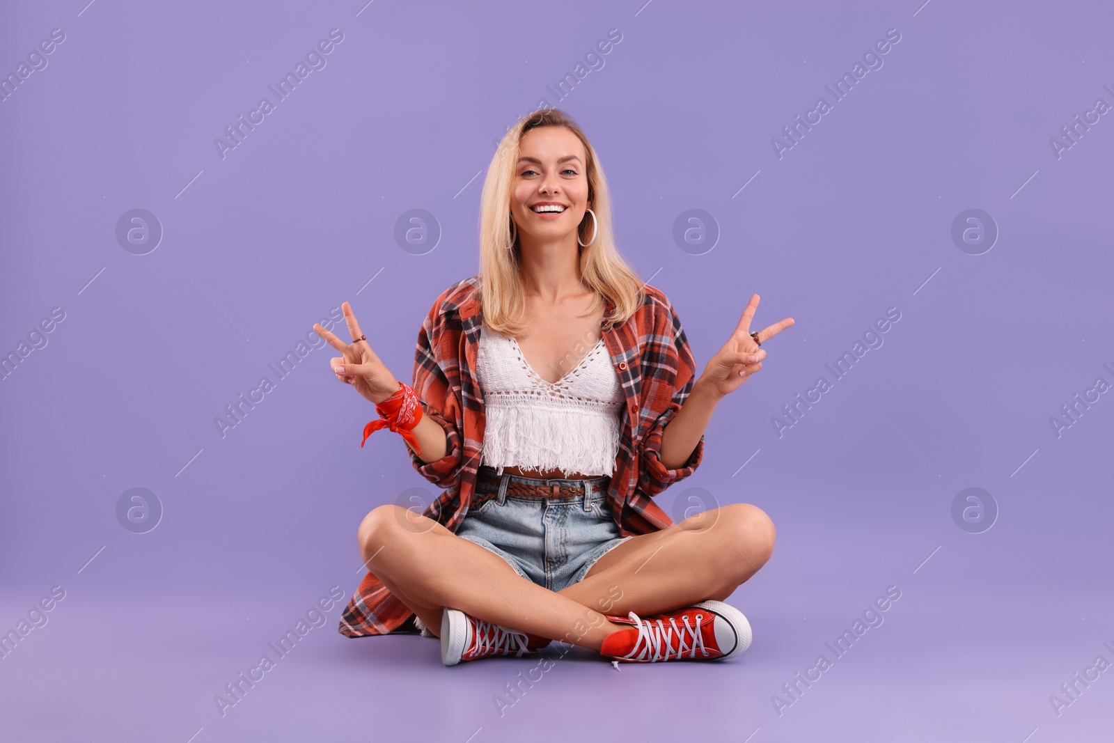 Photo of Happy hippie woman showing peace signs on purple background