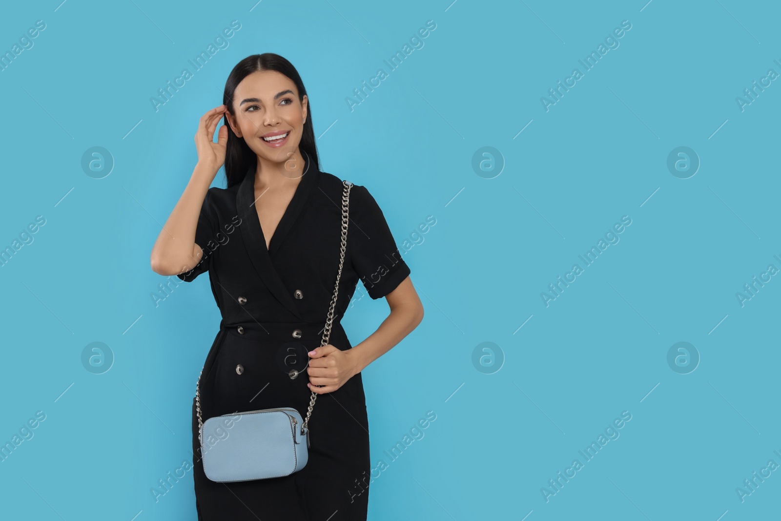 Photo of Beautiful young woman with stylish bag on light blue background, space for text